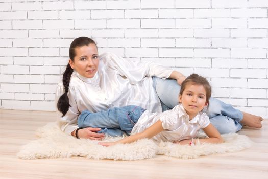 Mother and 5 year old daughter lying on a white fur rug at home