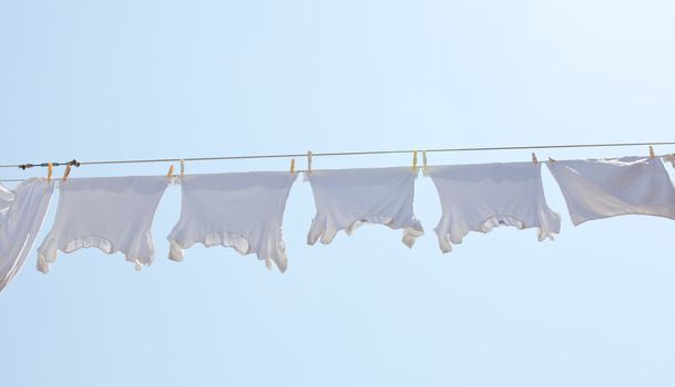 White t-shirt hanging to dry on a clothes-line.