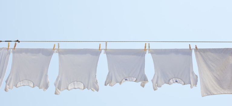 White t-shirt hanging to dry on a clothes-line.