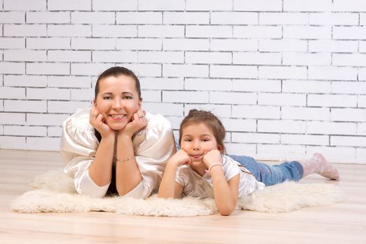 Mother and 5-year-old daughter lying on the floor resting his face with his fists