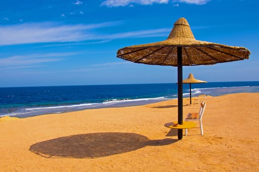 Picture of a beach view with an umbrella and bench