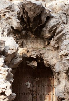 A rock archway over an entry with a wooden door.