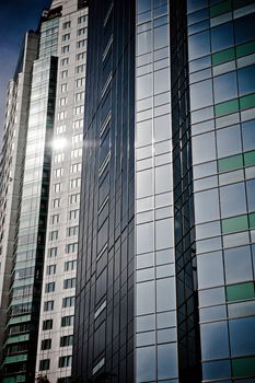 Windows on a group of skyscrapers with reflections of the sun.