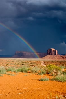 Rainbow on dark threatening sky at Monument Valley National Park