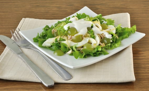 Salad with chicken in lettuce leaves with egg, cheese, yogurt and grapes under