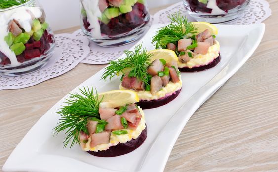 Appetizer of herring with onions on the beets and eggs, lemon and dill