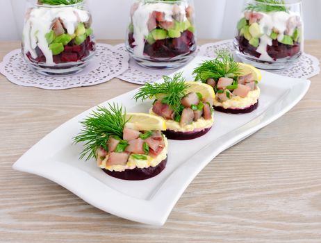  Appetizer of herring with onions on the beets and eggs, lemon and dill