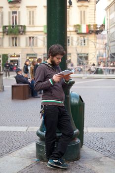 Boy reading a book in the Turin square, Italy