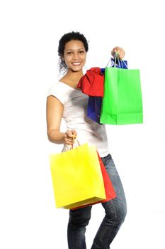 Happy African American woman shopper returning from a spending spree carrying handfuls of colourful shopping bags with her purchases