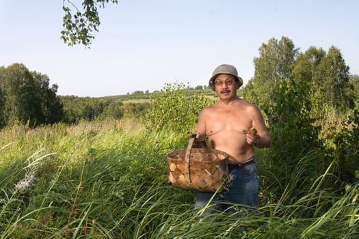 The man in a wood with a basket and a mushroom