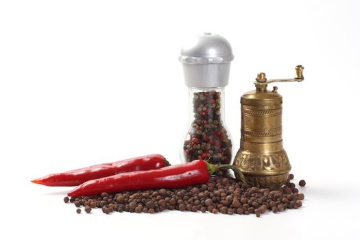 Two pepper mills, peppercorn and two pepper chillies