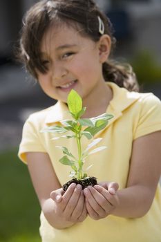 Pretty Asian girl holding plant in her hands