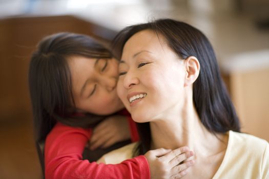Asian daughter hugging and kissing mother