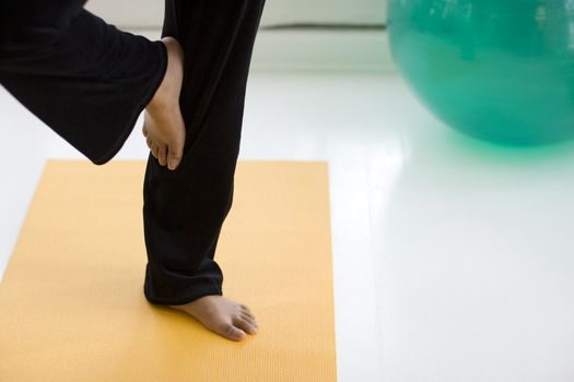 Young African American woman in yoga Tree pose only legs showing