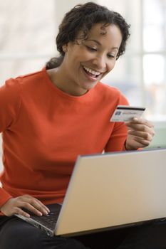 Smiling African American woman shopping online with credit card and laptop computer