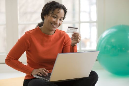 Smiling African American woman shopping online with credit card and laptop computer