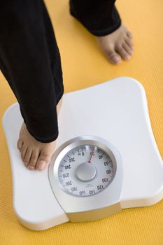 African American Woman weighing herself on a bathroom scale