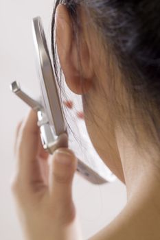 Close up view from behind of young woman making a cell phjone call