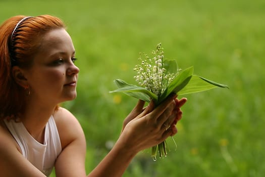 The girl with a bouquet of lilies of a valley on a green background