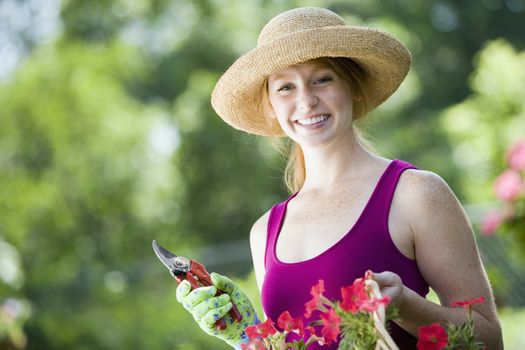Smiling young woman cutting flowers in her garden