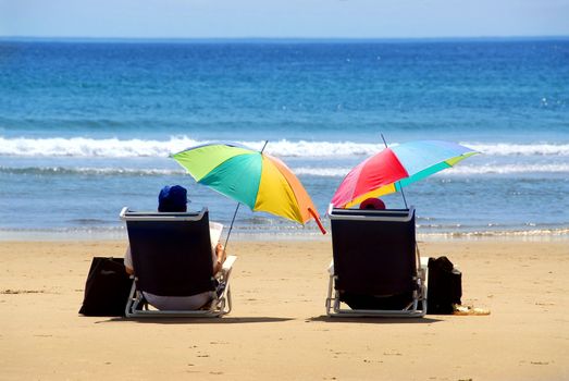 A couple relaxing on a beach under colorful umbrellas