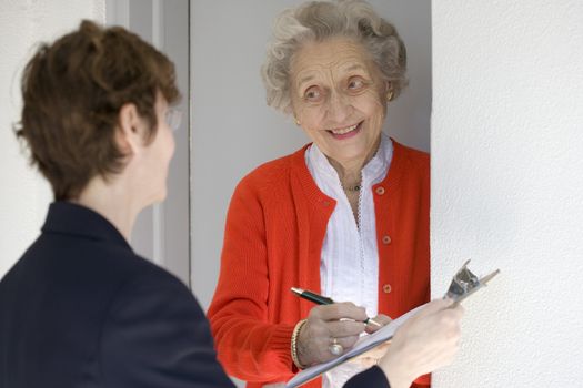 Attractive senior woman signing a document at her front door