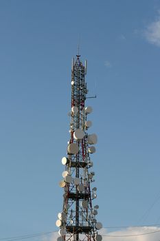 communications antena tower full of dishes with sky background