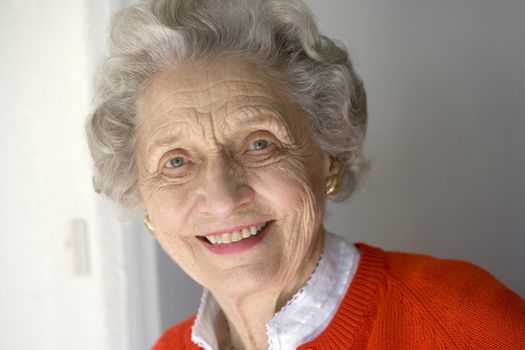 Portrait of attractive senior woman standing by front door