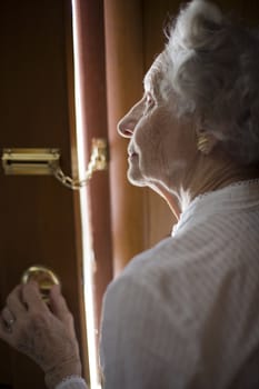 Senior woman using a security chain on front door