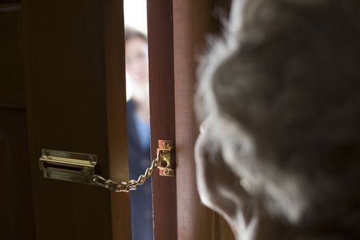 Senior woman using a security chain on front door
