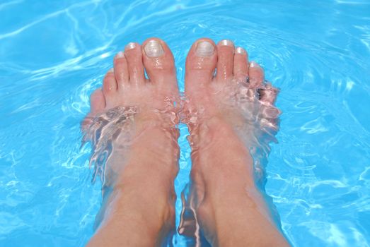 Woman's feet cooling in clear blue water