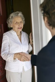 Senior woman shaking hands at her front door