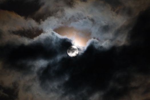 The moon shines through clouds at night