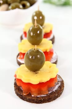 Canapes with cheese, red peppers and olives