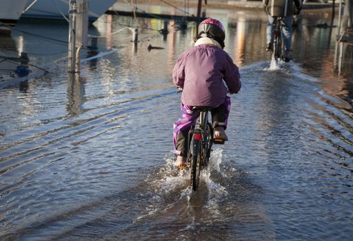 Kid having fun riding through the flooding in the harbor of Nyborg, Denmark after some days with heavy storm.