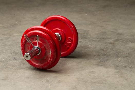 red dumbbells on a cement floor - sport concept