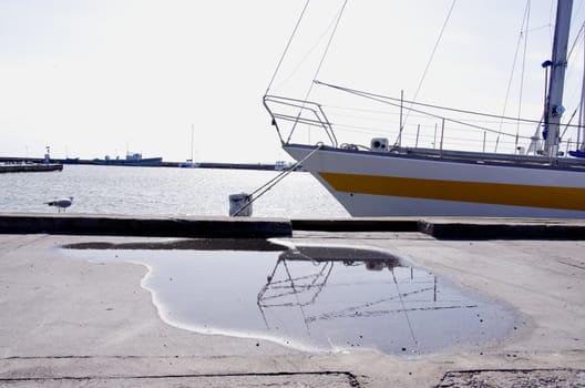 Yacht resting moored at the port. Seagull near water pool and pier.