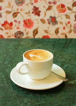 Cappuccino or latte coffee on table with flower chair