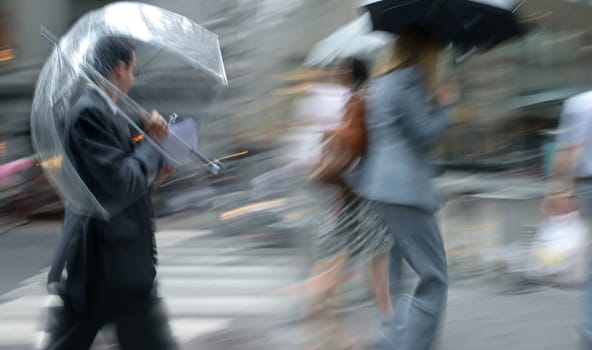 business people rushing on the rainy street in intentional motion blur