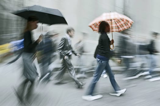 people rushing on the rainy street in intentional motion blur