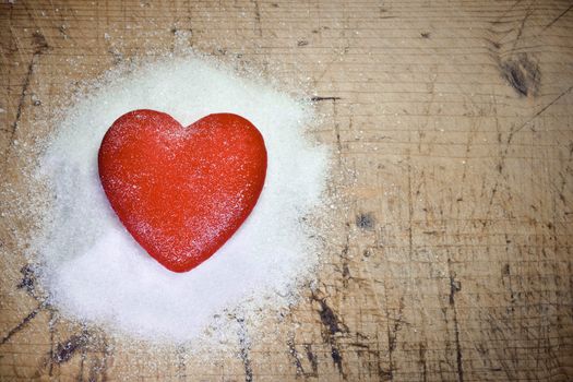 Read heart sitting on sugar on wood background