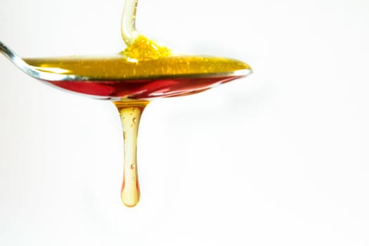 honey pouring in a spoon on white background