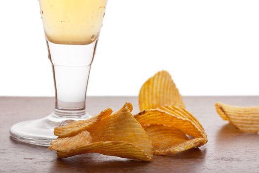 Mug of beer and some chips on a table.