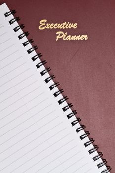 a maroon executive planner with spiral note book in portrait orientation