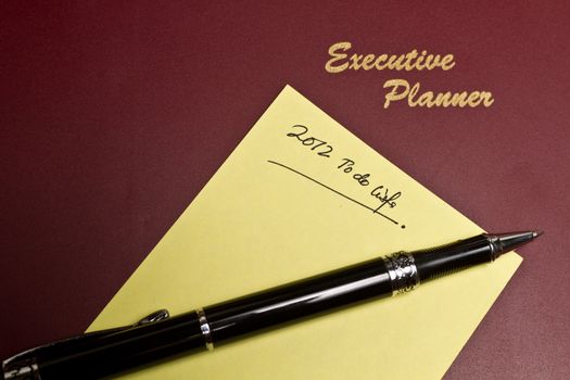 executive planner with yellow note pad and a pen in lanscape orientation