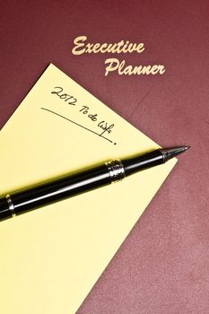 executive planner with yellow note pad and a pen in portrait orientation