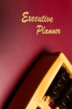 Angled view of a maroon excutive planner and traditional abacus in portrait orientation