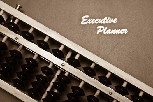 excutive planner and traditional abacus in sepia tone