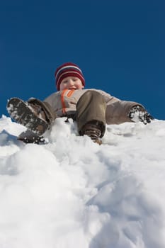 The boy moves down from an ice slope and laughs