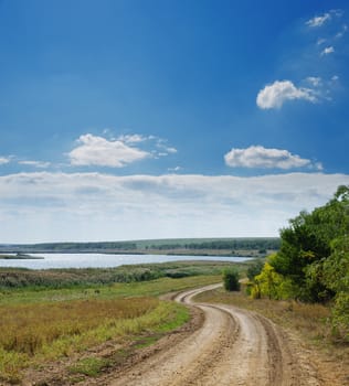 rural road near river under cloudy sky